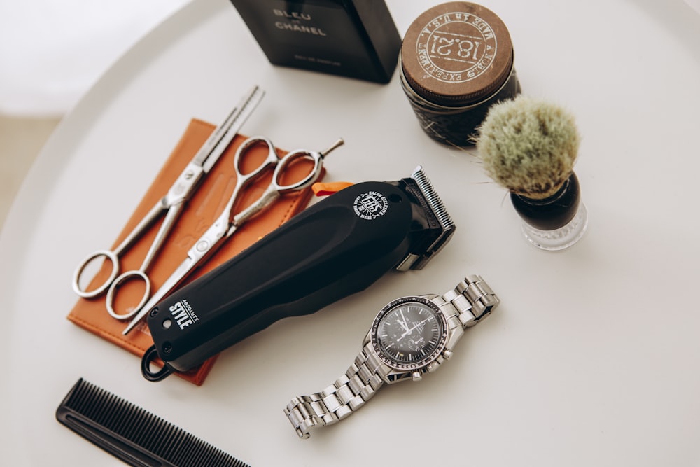 silver link bracelet round analog watch beside black leather pouch and silver and gold link bracelet