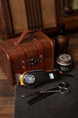 black and silver hair brush beside brown suitcase