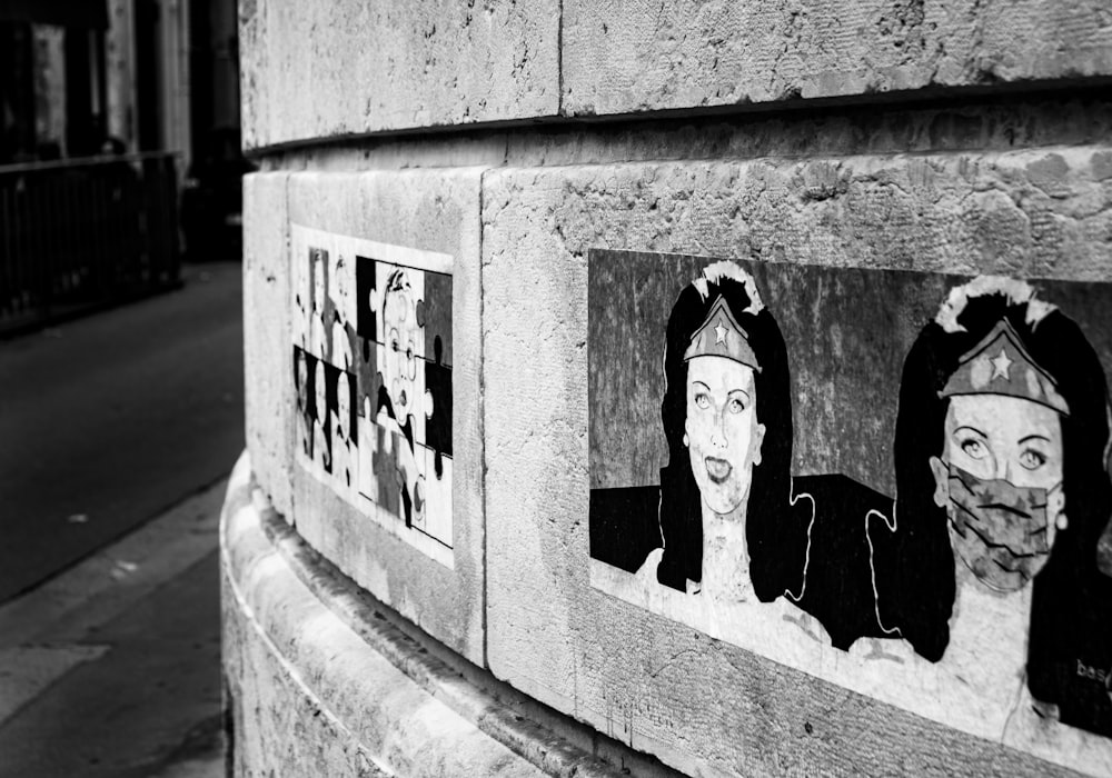 foto in scala di grigi di 2 donne in piedi sul muro