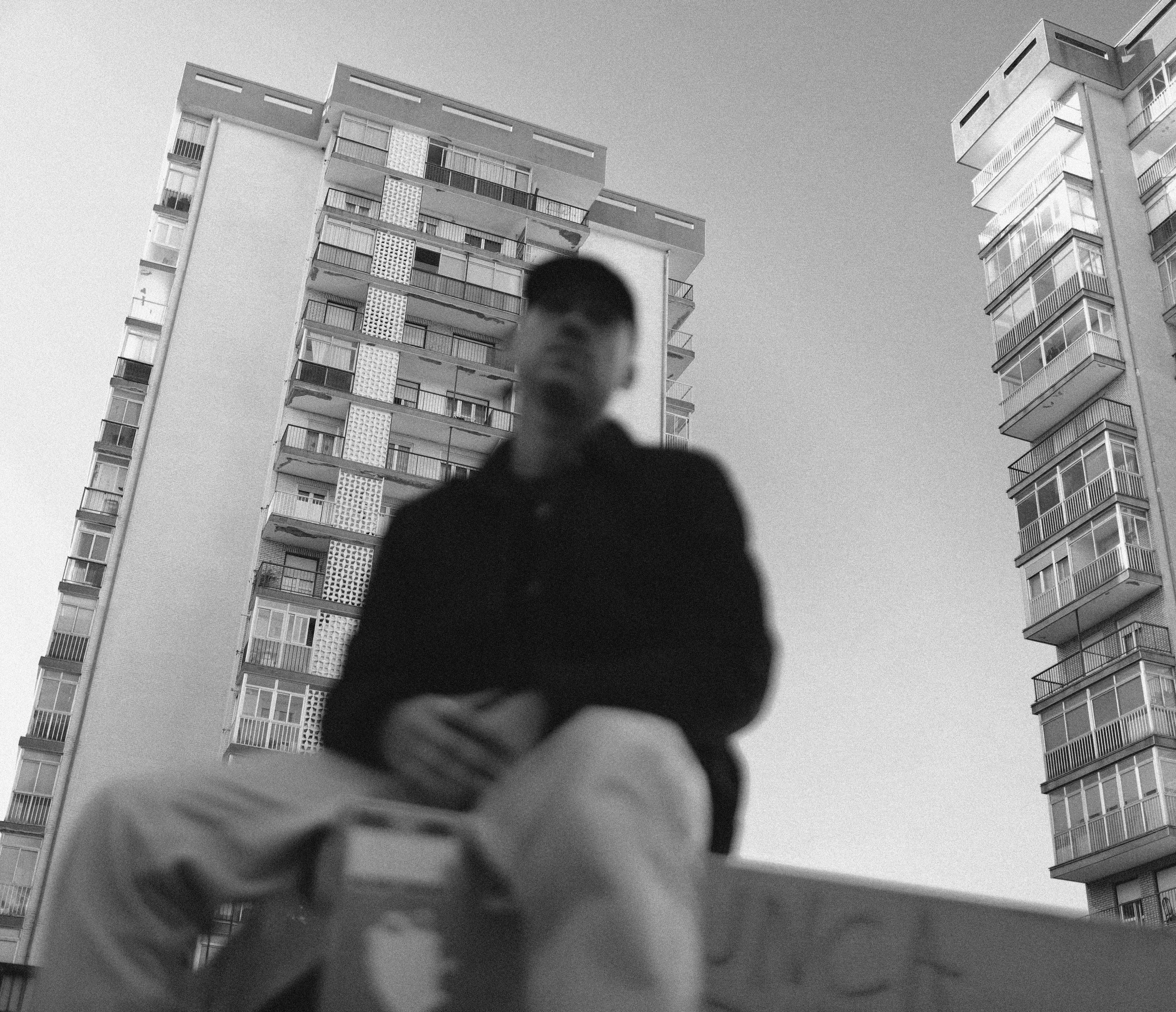 man in black jacket sitting on the edge of a building