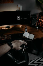 A sleek, dark-toned office desk with a vintage brass lamp and a leather-bound notebook beside a laptop displaying rail logistics data.
