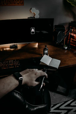 A sleek, dark-toned office desk with a vintage brass lamp and a leather-bound notebook beside a laptop displaying rail logistics data.