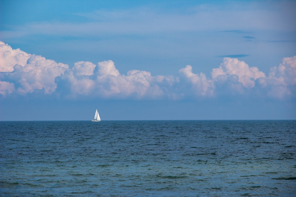Segelboot auf See unter weißen Wolken und blauem Himmel tagsüber