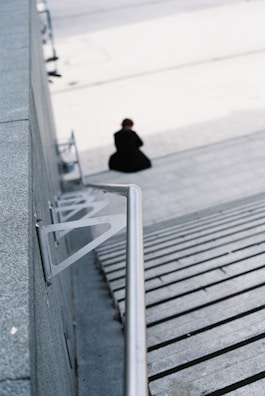 person in black jacket sitting on wooden stairs