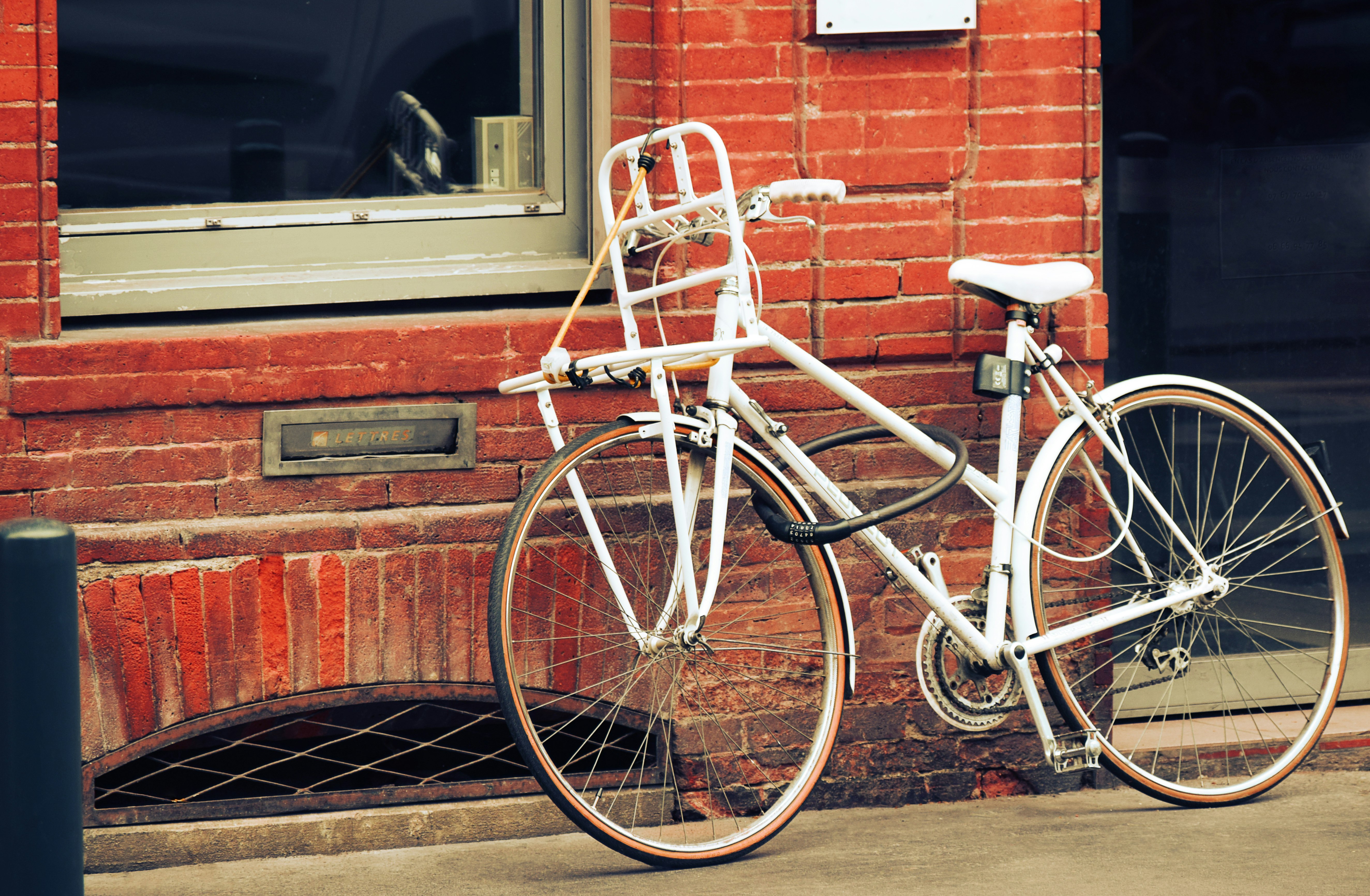 white city bike parked beside brown brick wall