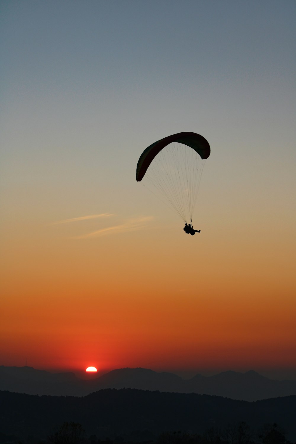 Silueta de la persona que monta el paracaídas durante la puesta del sol
