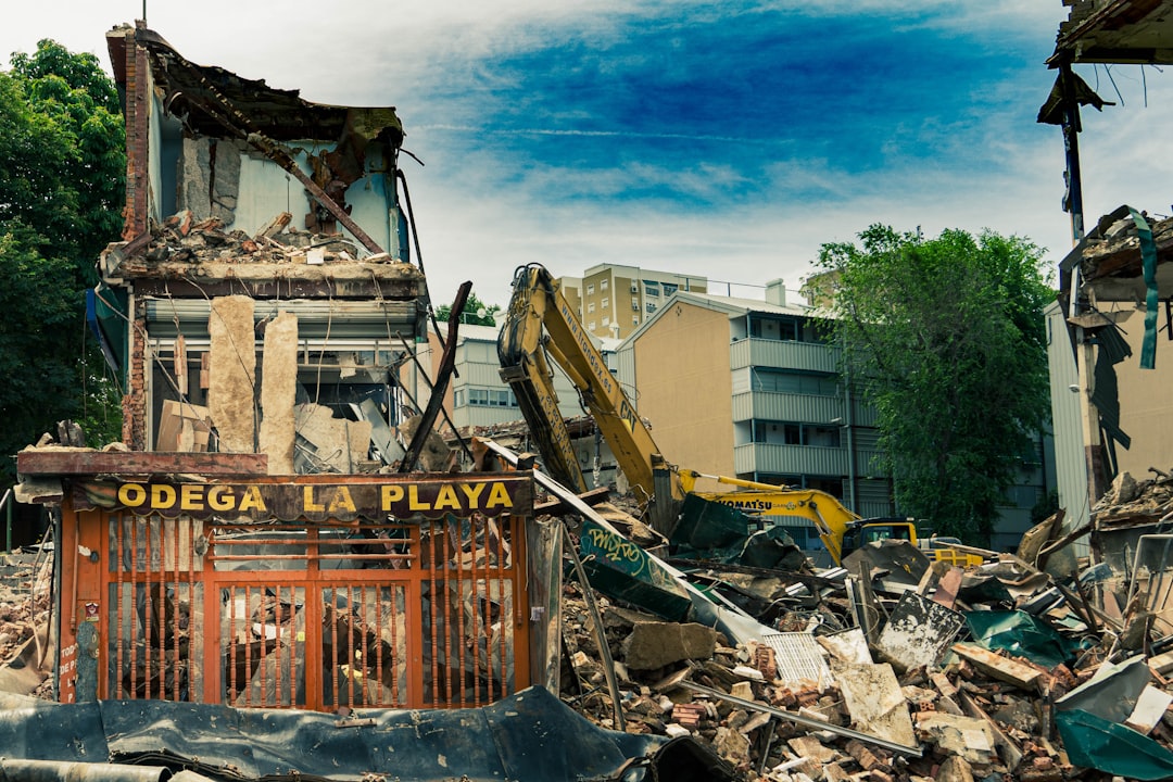 yellow excavator near white concrete building during daytime