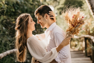 A joyful couple exchanging vows outdoors under a rustic wooden arch.
