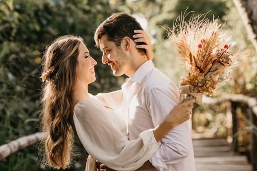 A couple sharing a joyful embrace under a blooming archway surrounded by lush greenery.