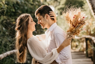A joyful couple holding hands in a sunlit garden, surrounded by blooming flowers.