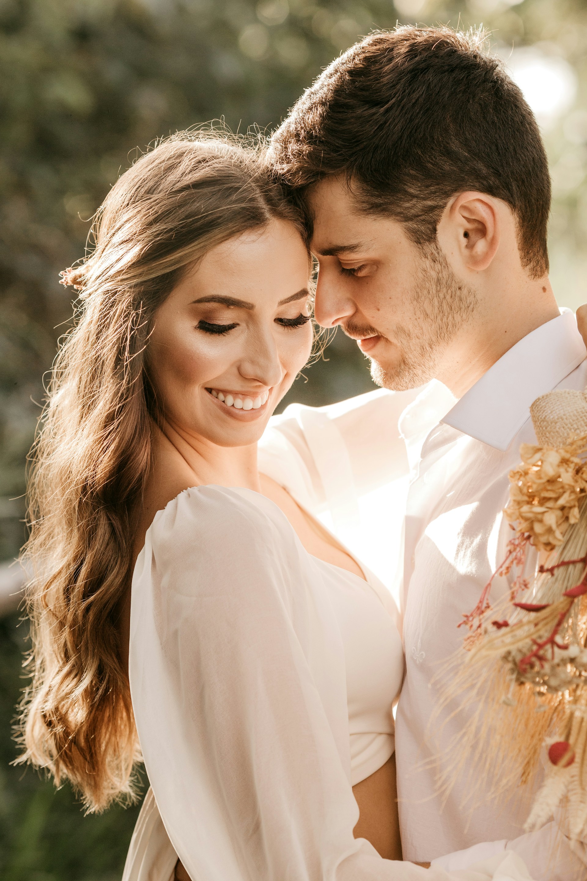 man in white suit kissing woman in white dress