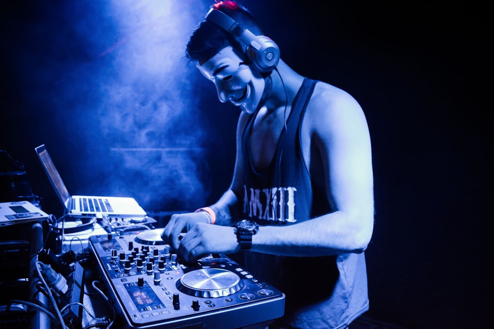 Mann in schwarzem Tanktop spielt DJ-Mixer