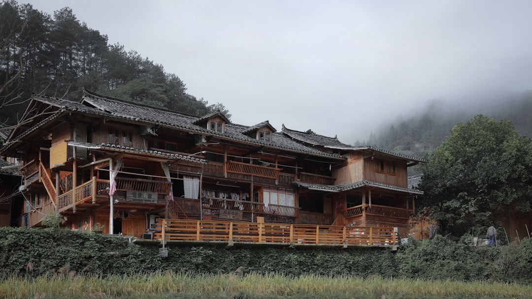 brown wooden house on green grass field under white cloudy sky during daytime