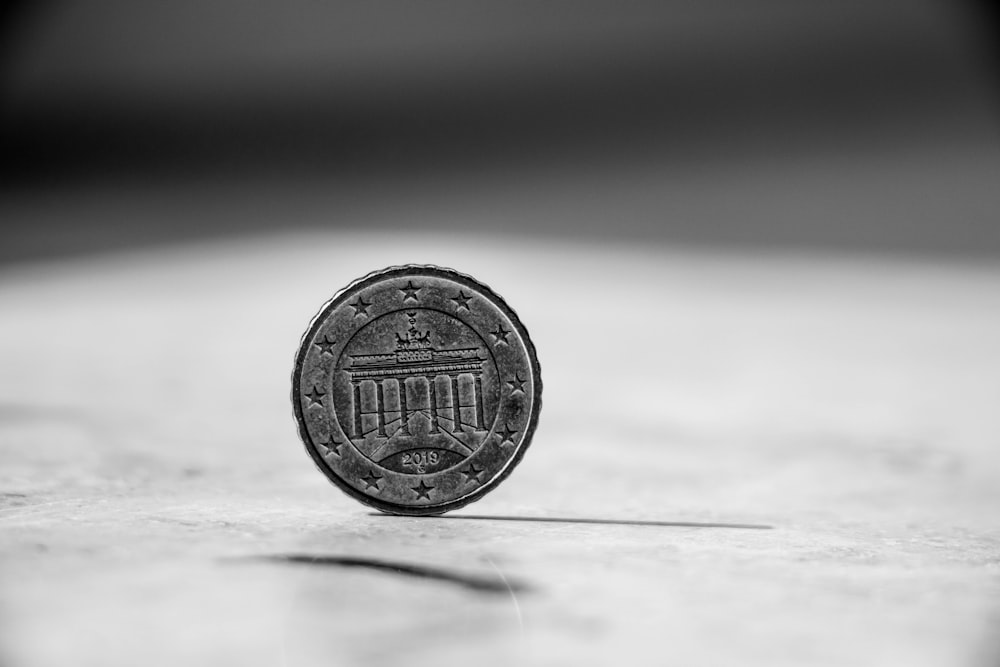 silver round coin on white surface