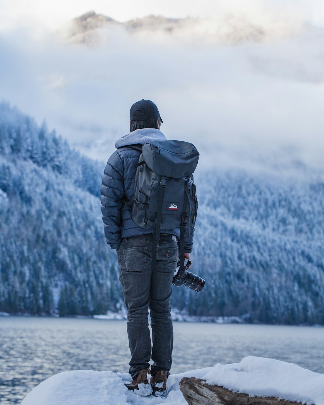 man in black jacket and black pants standing on snow covered ground during daytime