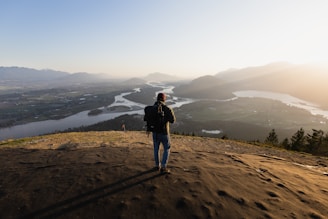 A traveler’s backpack resting on a wooden bench overlooking a serene mountain valley at sunset.