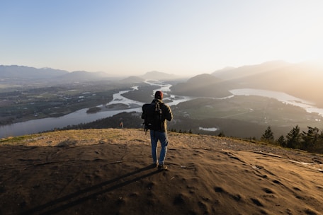 A traveler’s backpack resting on a wooden bench overlooking a serene mountain valley at sunset.
