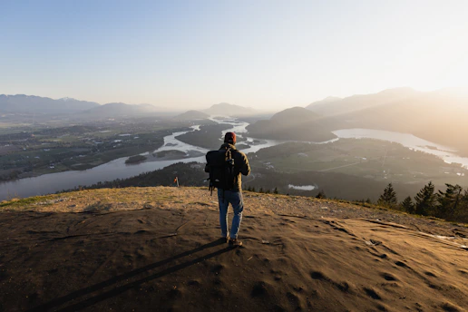 A scenic mountain trail with a backpacker enjoying the view at sunset.