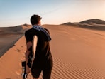 man in black jacket walking on desert during daytime