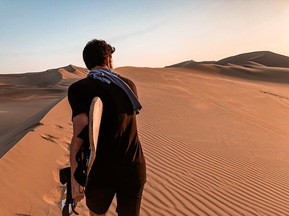 Mann in schwarzer Jacke geht tagsüber durch die Wüste