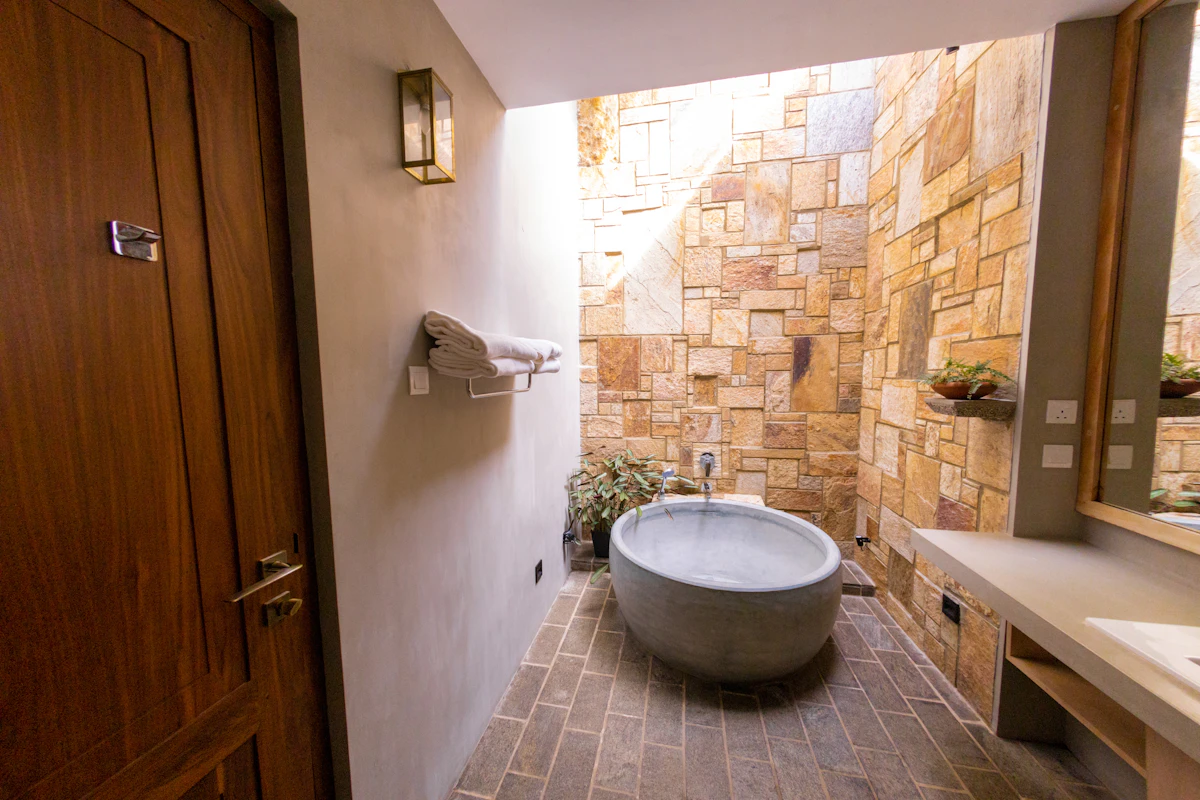 Baño con pared de piedra y bañera exenta