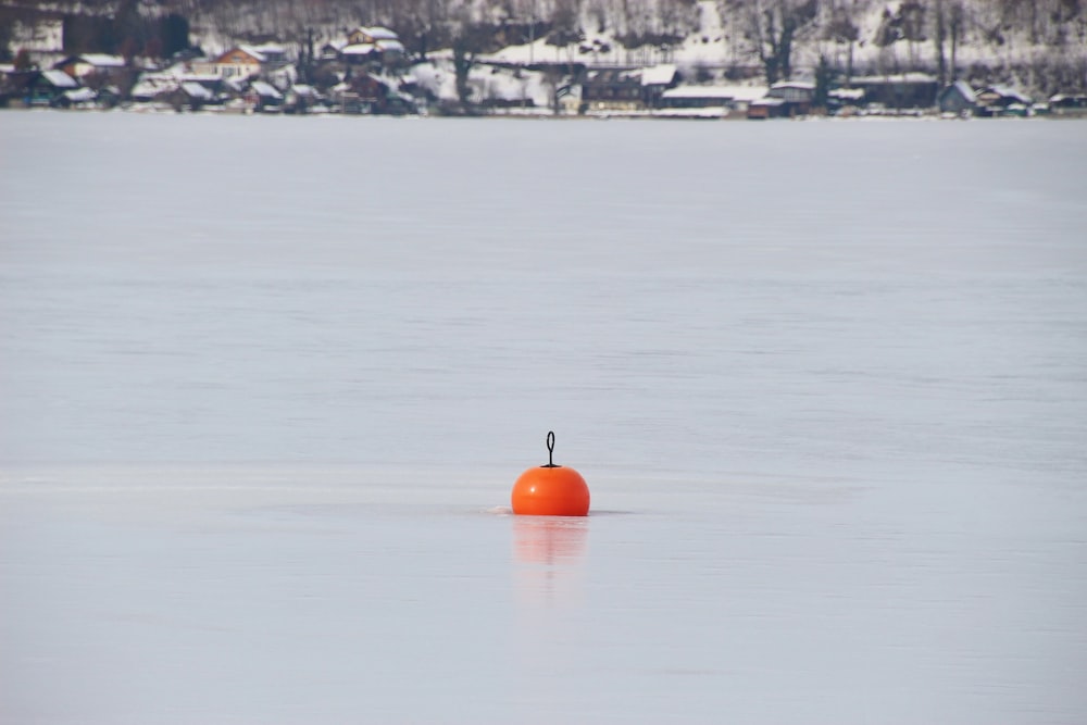 orange and black kettle bell on snow covered ground during daytime