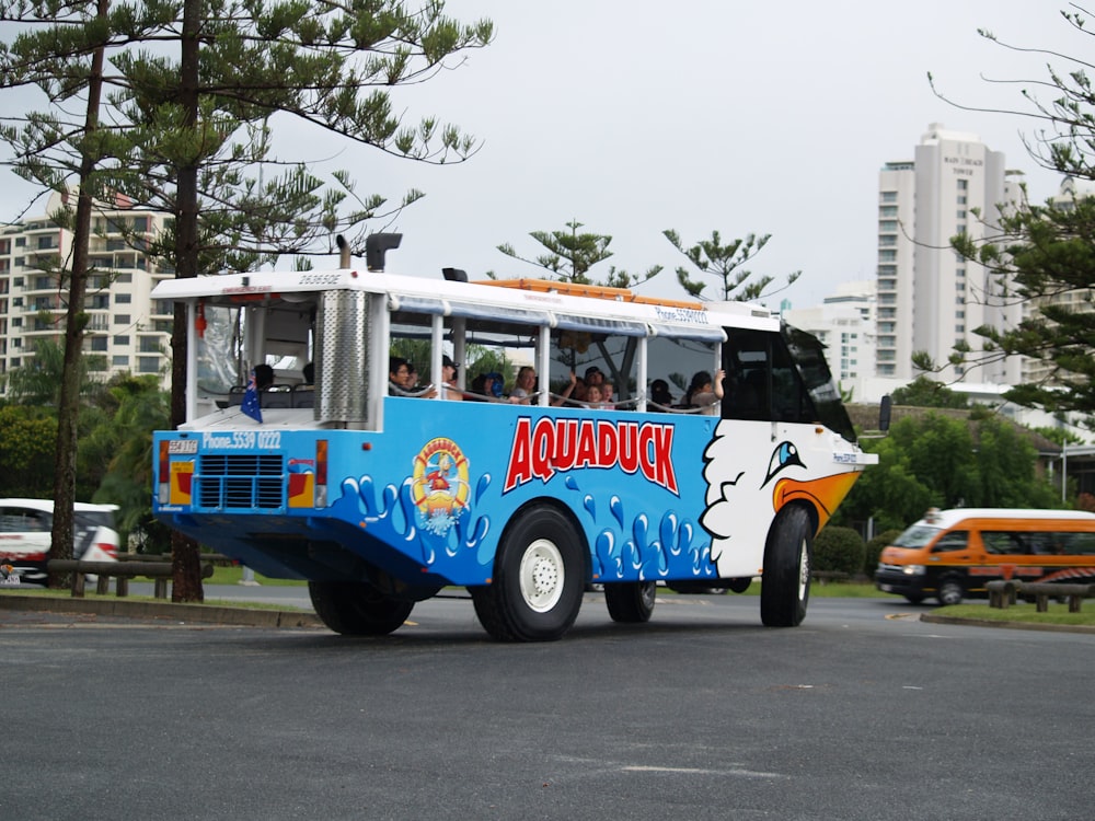 people riding on blue and white car on road during daytime