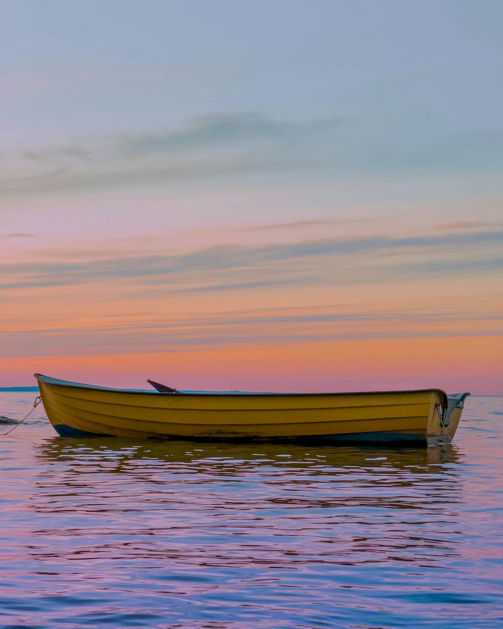 barca gialla sullo specchio d'acqua durante il tramonto