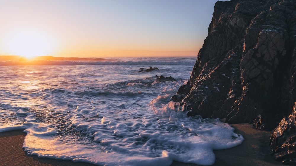 ocean waves crashing on rocky shore during sunset