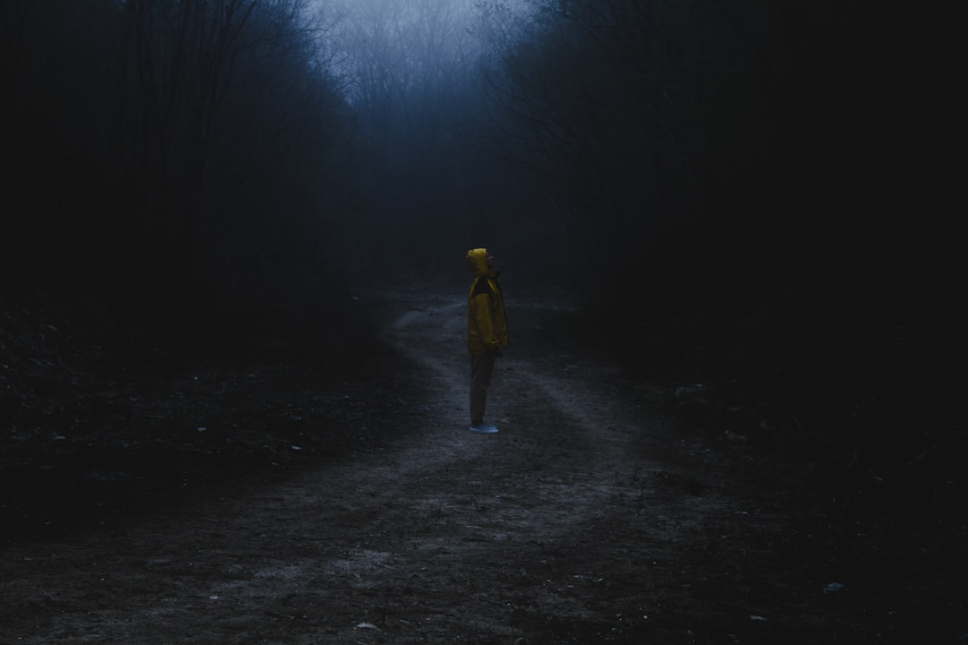 man in yellow jacket and gray pants standing on road during daytime