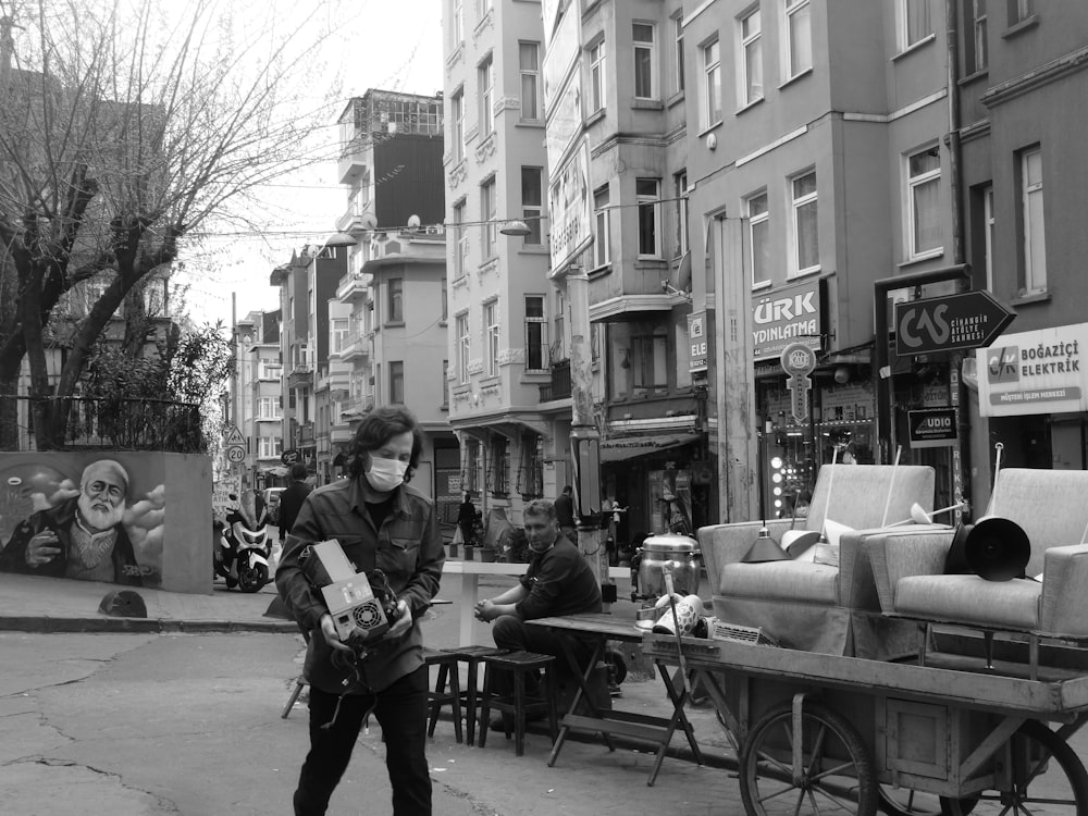 grayscale photo of man and woman standing on sidewalk