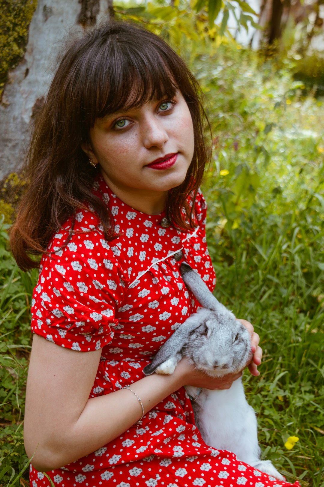 girl in red and white polka dot shirt holding gray rabbit