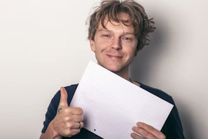 A happy student holding up a completed homework sheet with a tutor smiling beside.