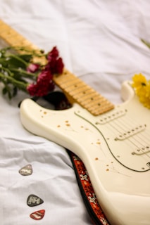 white stratocaster electric guitar on white textile