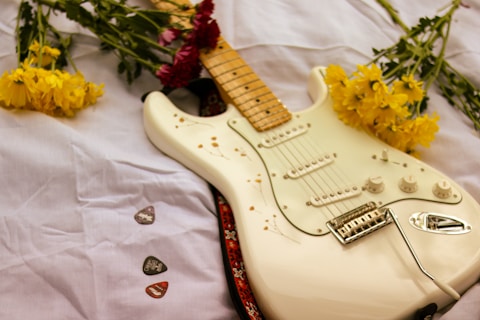 white stratocaster electric guitar on white textile