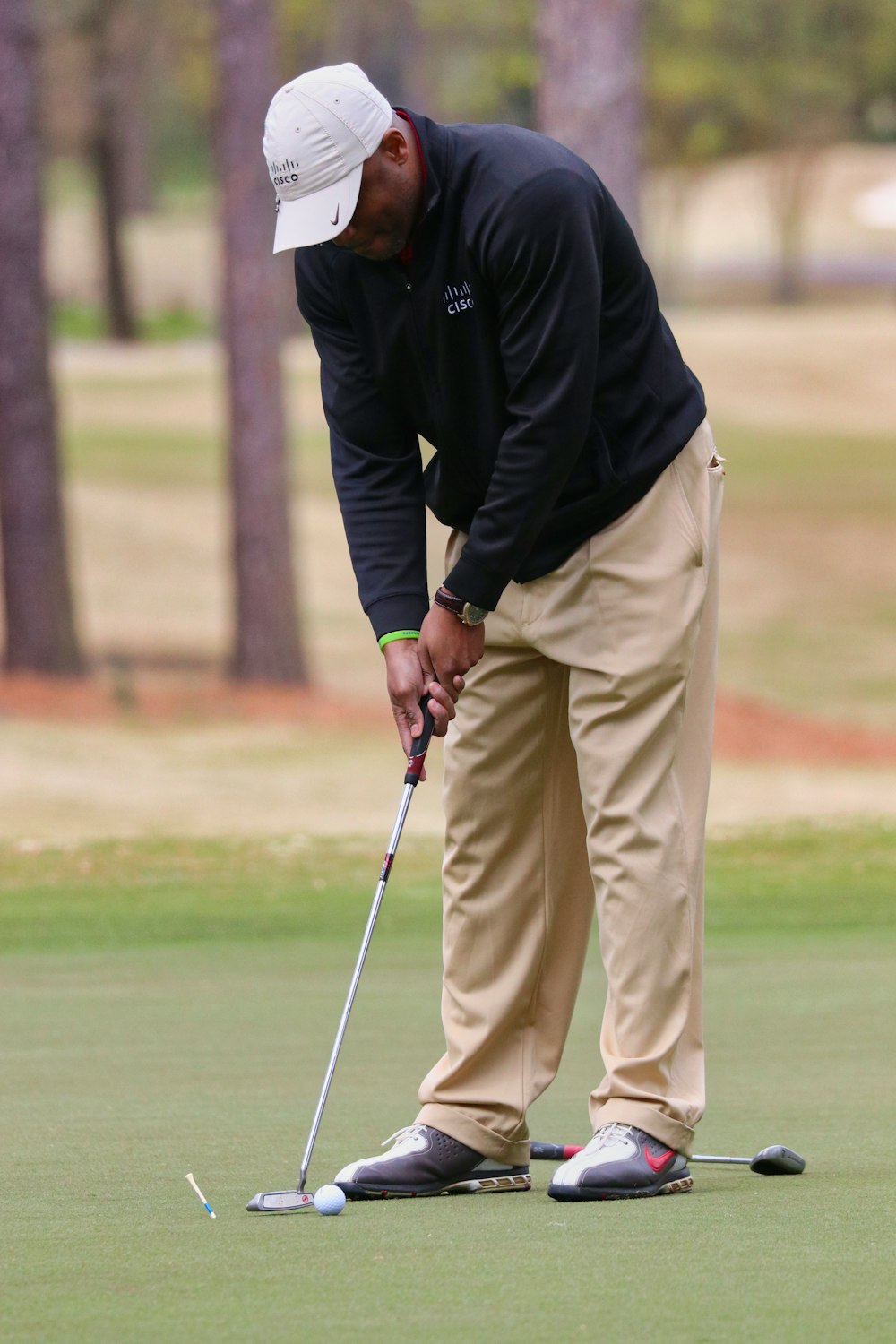 man in black jacket and beige pants playing golf during daytime