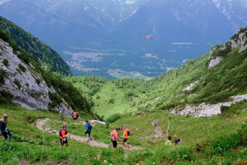 people on green grass field near green mountains during daytime