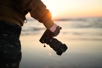 A photographer capturing a couple during a sunset at the beach.