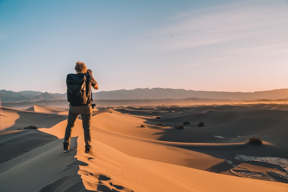 donna in giacca nera in piedi su sabbia marrone durante il giorno
