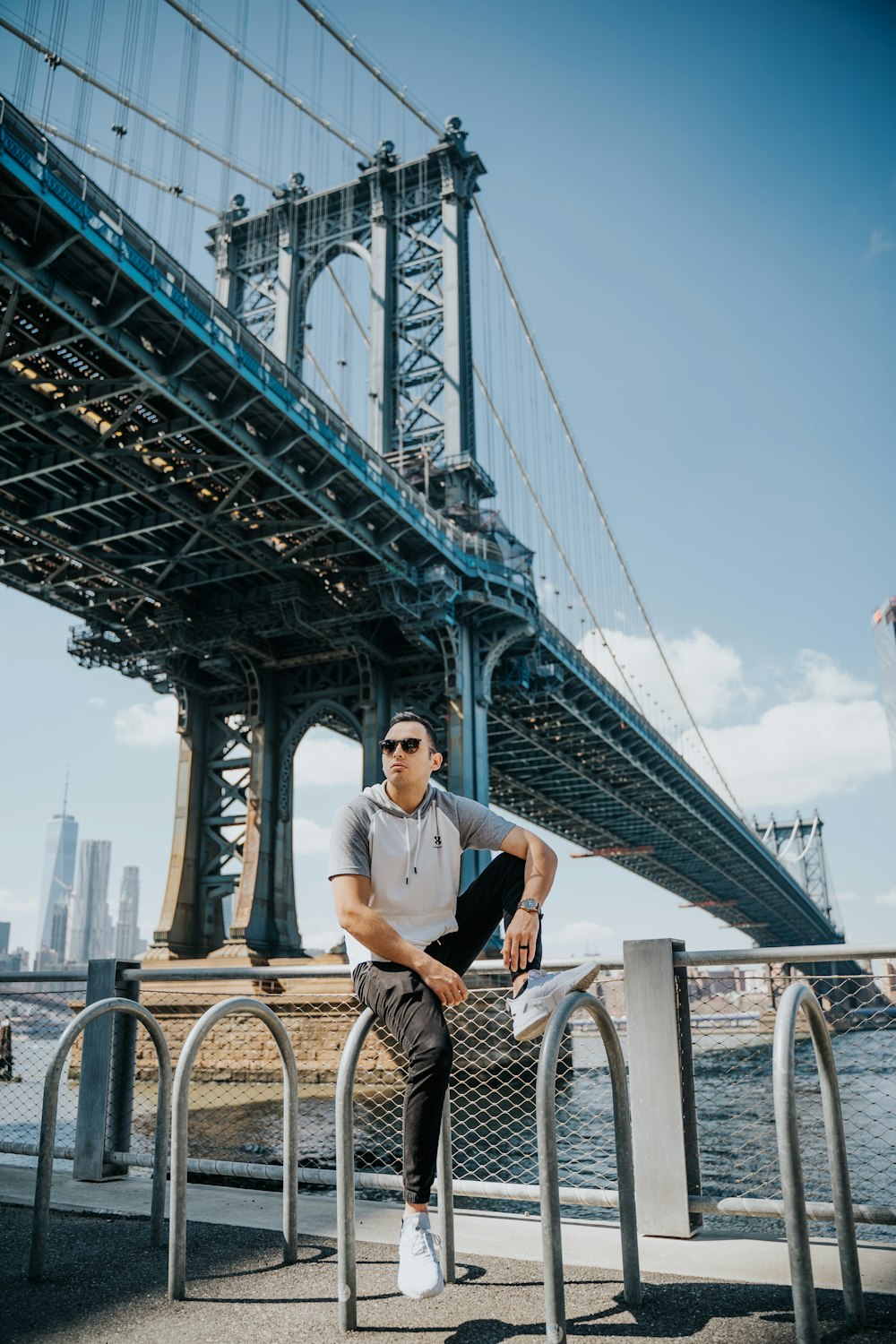 man in white shirt sitting on bicycle near bridge during daytime