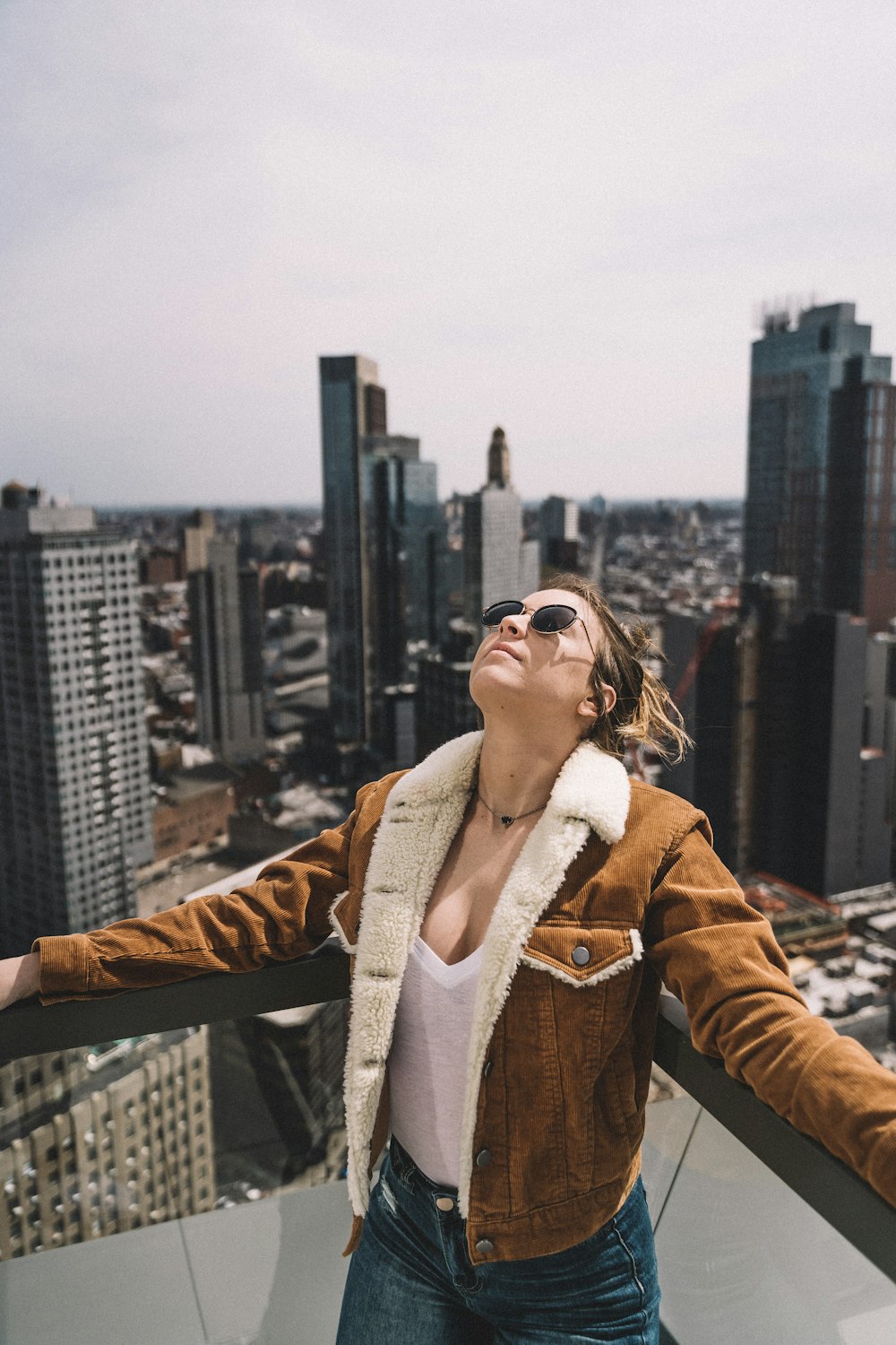 woman in brown coat standing on top of building during daytime