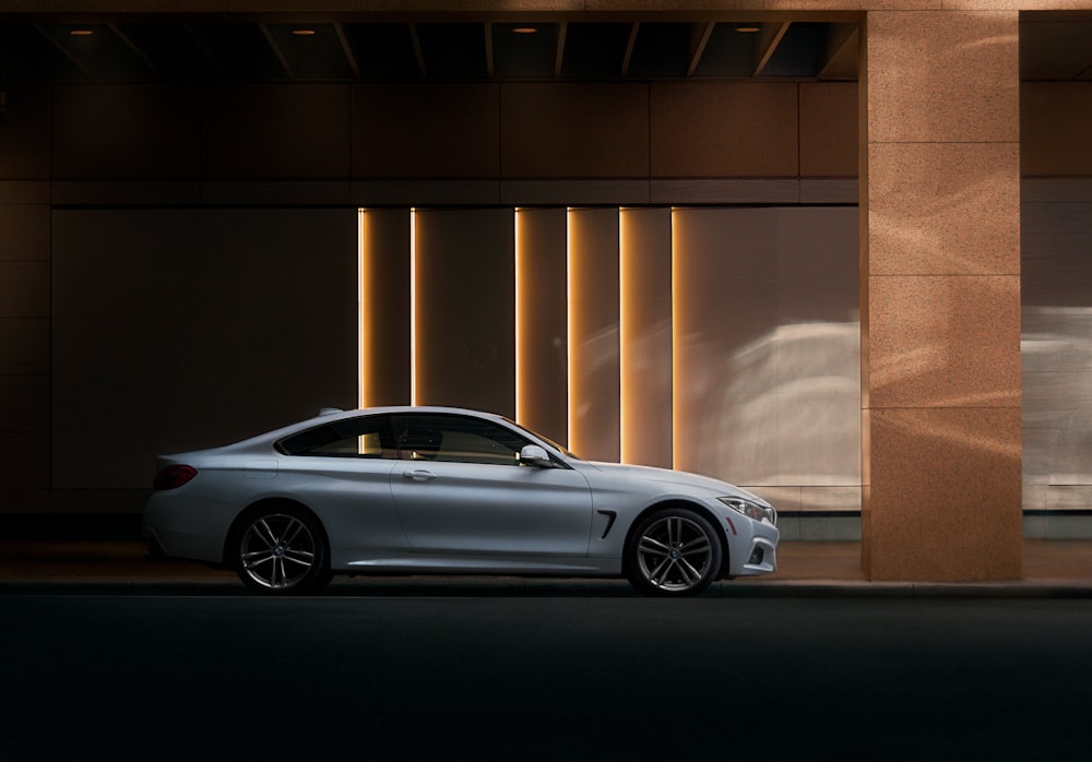 silver coupe parked beside brown wall