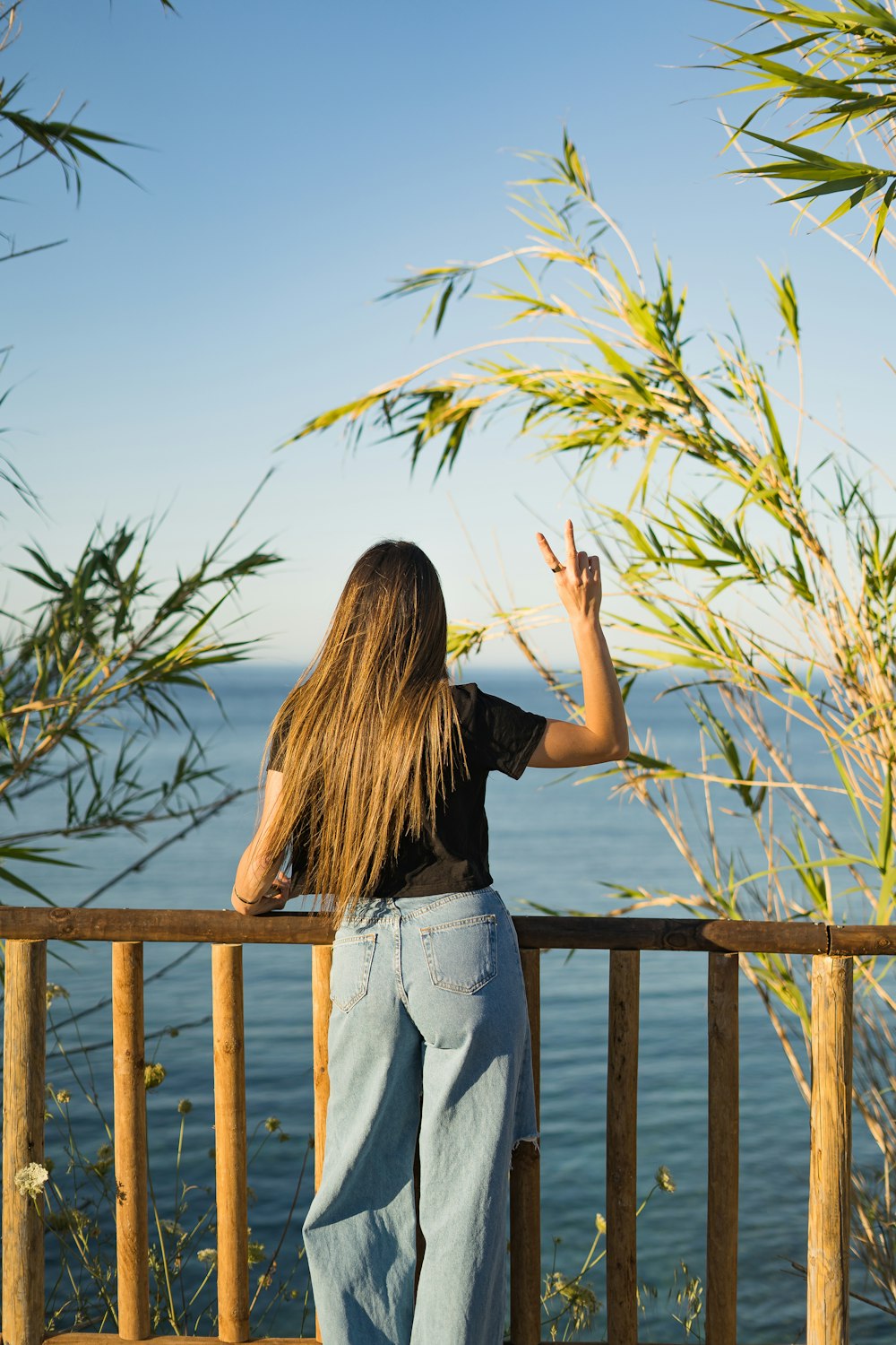 woman in black shirt and gray denim jeans standing on wooden dock during daytime