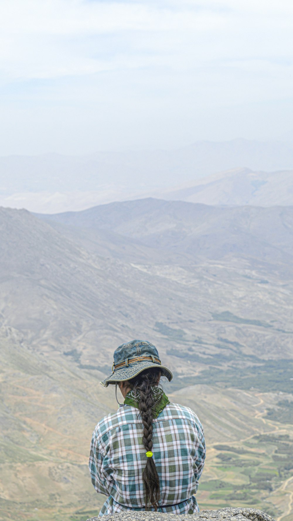 Hombre con sombrero blanco y negro y chaqueta negra de pie en la cima de la montaña durante el día