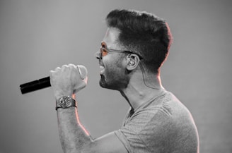 Close-up of the lead singer with retro sunglasses singing passionately into a vintage microphone.