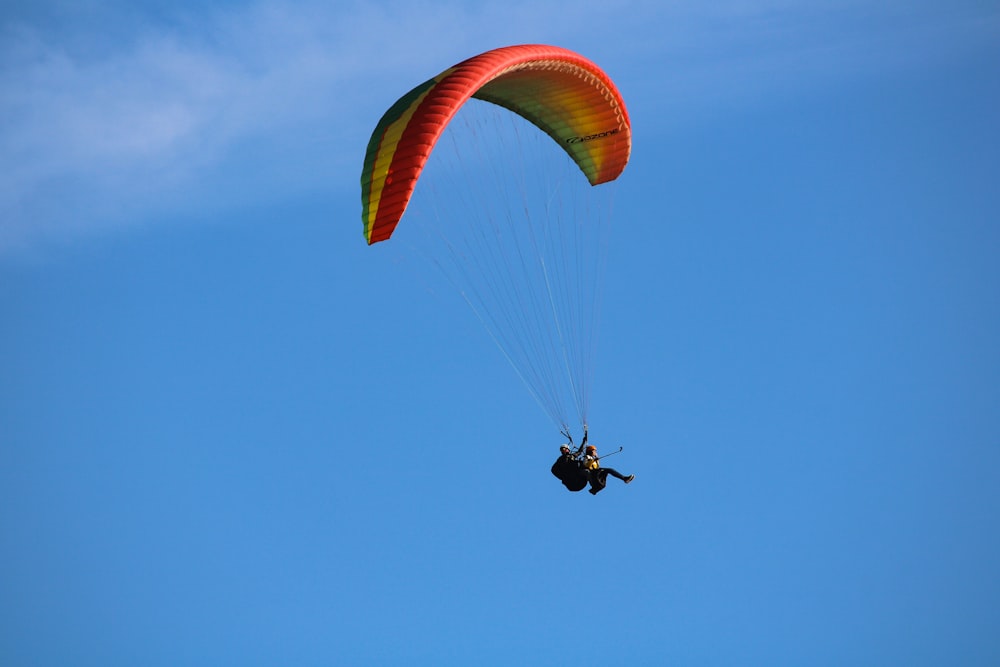 personne en parachute jaune sous ciel bleu pendant la journée