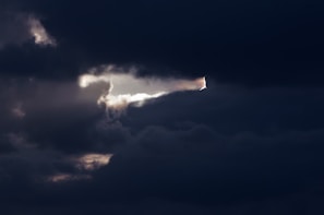 Action shot of a quarterback mid-throw, framed by a dramatic gray sky hinting at intense competition.