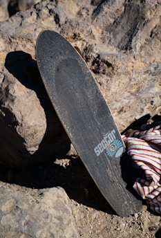 A close-up of a handcrafted eucalyptus wood skateboard deck with the himalayandeck logo, resting on a sunlit concrete ramp.