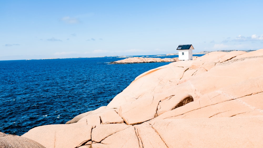 white and brown house on white rock formation near blue sea under blue sky during daytime