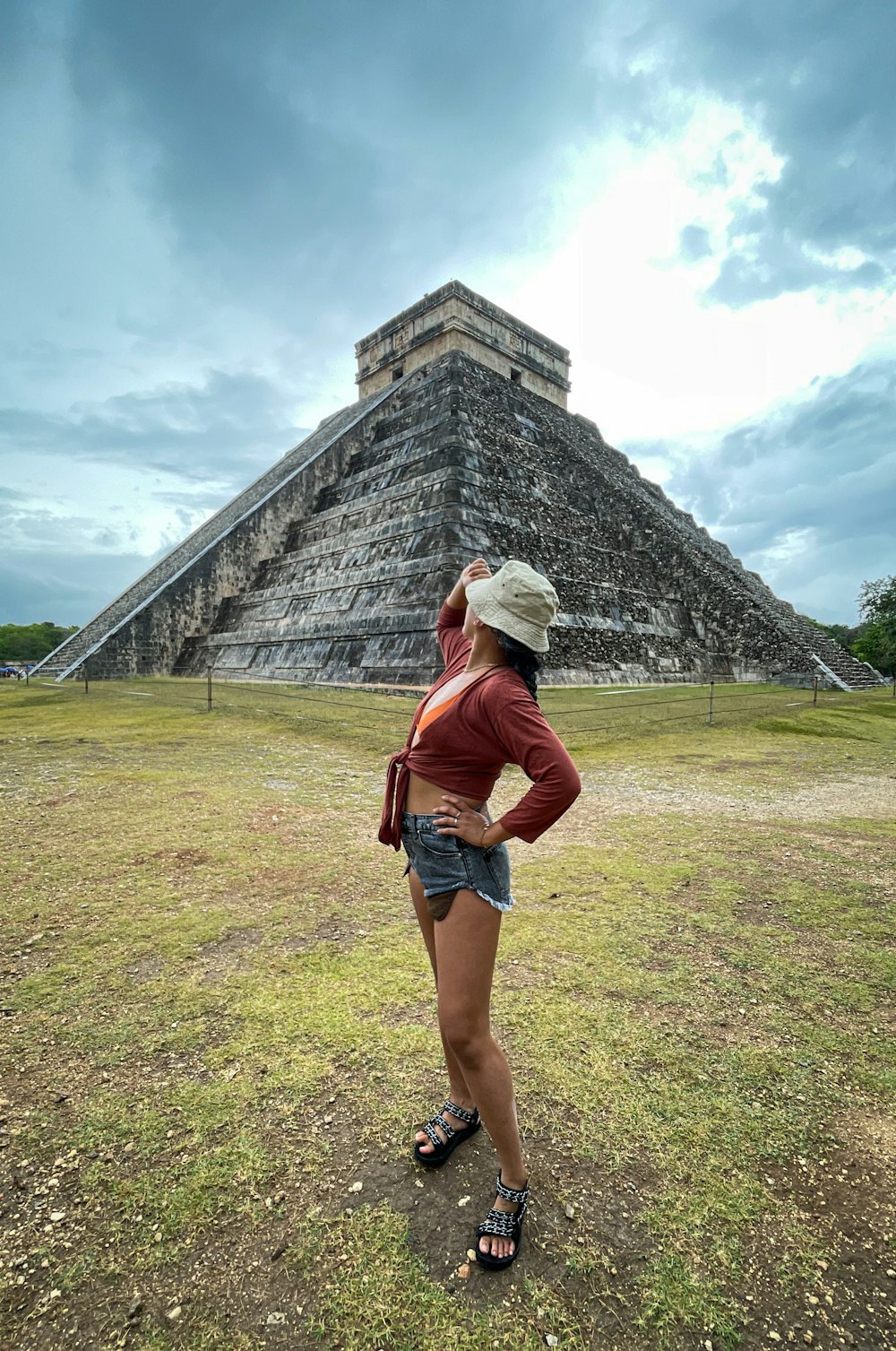 woman in brown jacket standing near pyramid during daytime